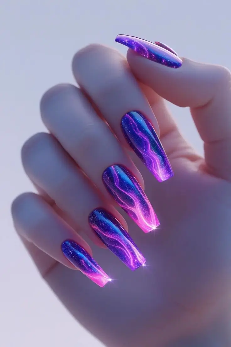 Close-up of a hand with long coffin nails featuring a neon galaxy aura nail art design with vibrant purple and green gradient and glowing light streaks, showcasing a futuristic and trending look for US manicures.