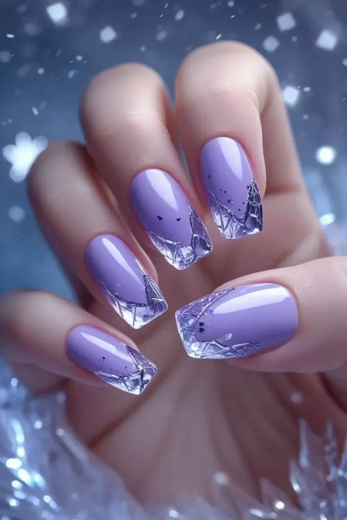Close-up of a hand with square-shaped nails featuring frozen lavender crystal nail art with a lavender ombre fade to clear tips with silver geometric ice patterns, showcasing a chic and trending winter design for US manicures.