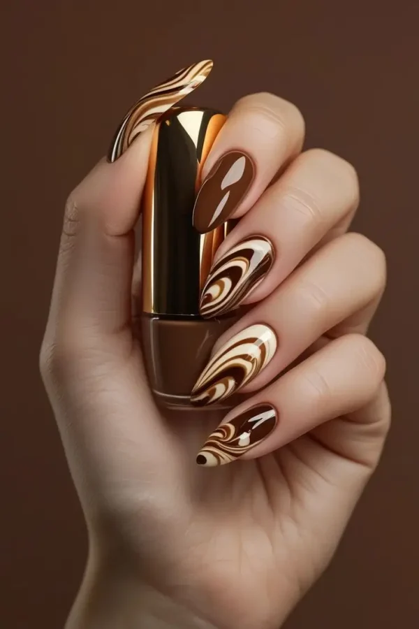 Close-up of a hand with long almond nails featuring glossy mocha swirl nail art with caramel, espresso, and cream marble patterns, showcasing a sophisticated and trending design for US manicures.