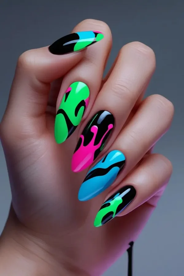 Close-up of a hand with long stiletto nails featuring neon drip art nail design with a black base and abstract patterns in electric green, hot pink, and blue, showcasing a bold and trending design for US manicures.