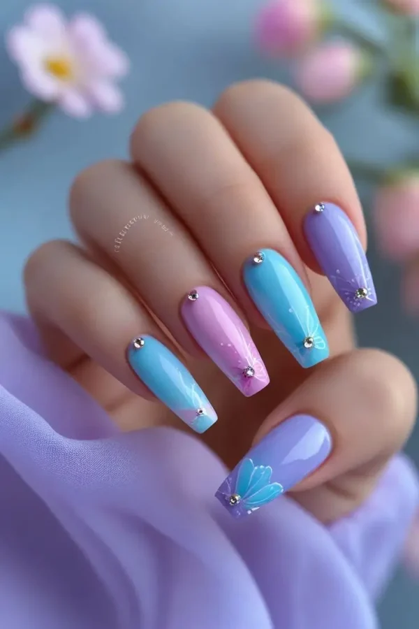 Close-up of a hand with long coffin nails featuring pastel butterfly dream nail art with pink, blue, and lavender colors, hand-painted wing details, and clear rhinestones, showcasing a whimsical and trending design for US manicures.