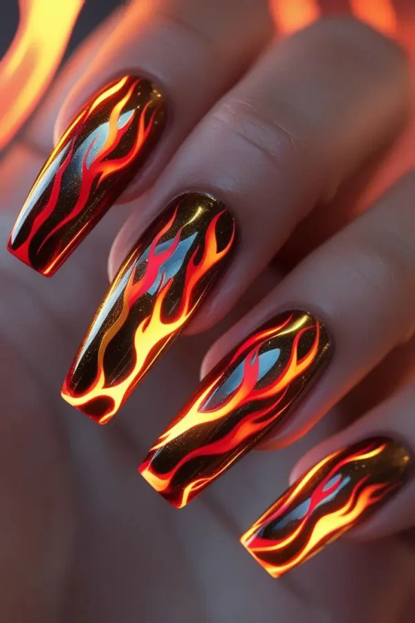 Close-up of a hand with long coffin nails featuring phoenix flame chrome nail art with bold red, orange, and gold gradients on a dark metallic base, showcasing a fiery and trending design for US manicures.