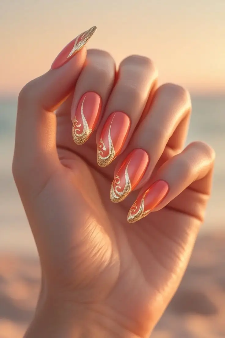 Close-up of a hand with long almond nails featuring sunset coral and gold swirl nail art with a warm orange base and intricate metallic gold glitter patterns, showcasing an elegant and trending design for US manicures.