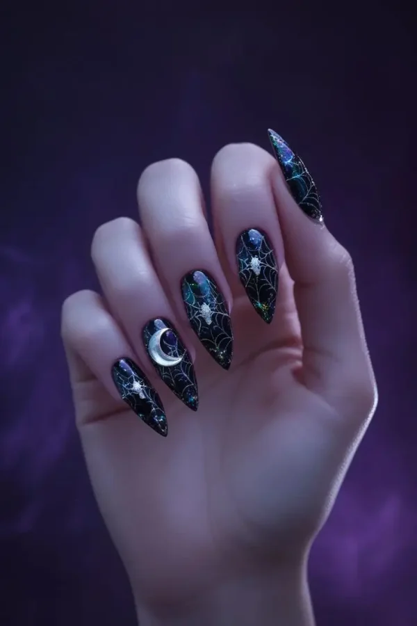 Close-up of a hand with long stiletto nails featuring holographic spiderweb goth nail art with a black base, iridescent spiderwebs, a silver moon, and star accents, showcasing a Halloween-inspired and trending design for US manicures.