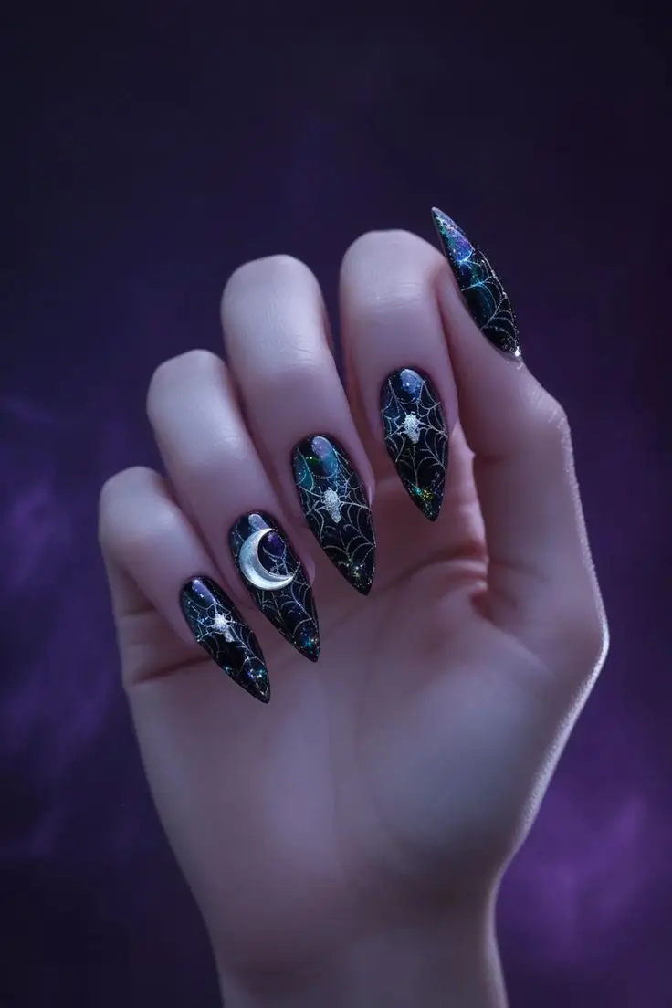 Close-up of a hand with long stiletto nails featuring holographic spiderweb goth nail art with a black base, iridescent spiderwebs, a silver moon, and star accents, showcasing a Halloween-inspired and trending design for US manicures.